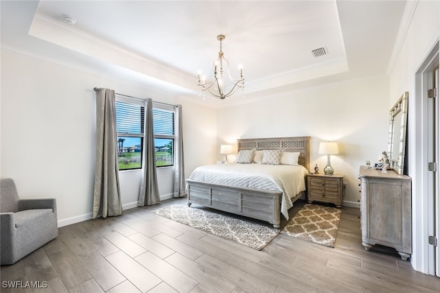 bedroom with crown molding, an inviting chandelier, and a tray ceiling