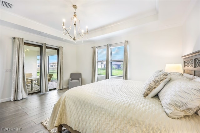 bedroom with a chandelier, a raised ceiling, and access to outside