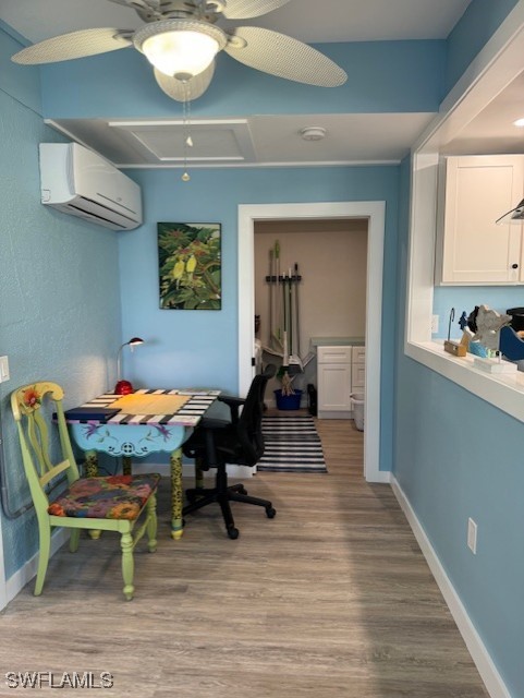 home office with a wall unit AC, light wood-style flooring, and baseboards