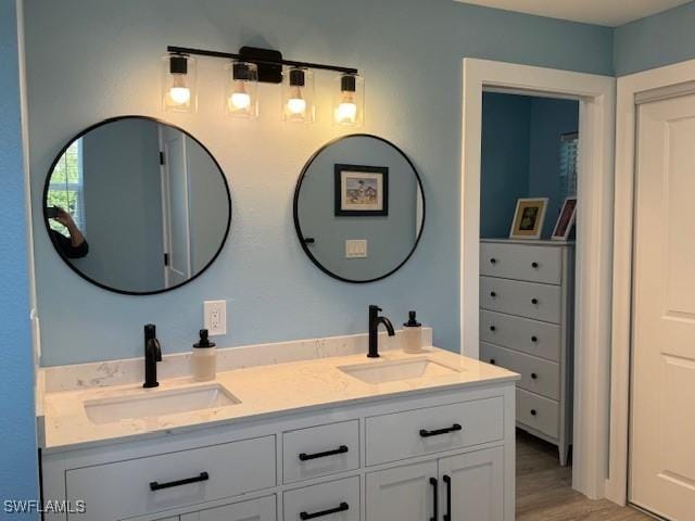 bathroom with double vanity, a sink, and wood finished floors