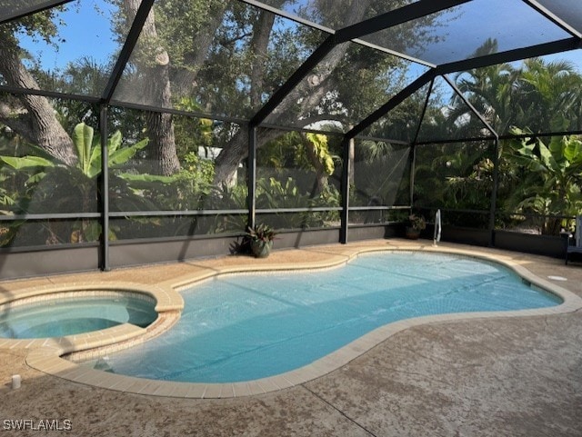 view of swimming pool with a patio area, a pool with connected hot tub, and glass enclosure