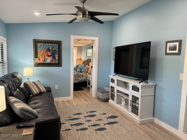 living room featuring a ceiling fan, baseboards, vaulted ceiling, and wood finished floors