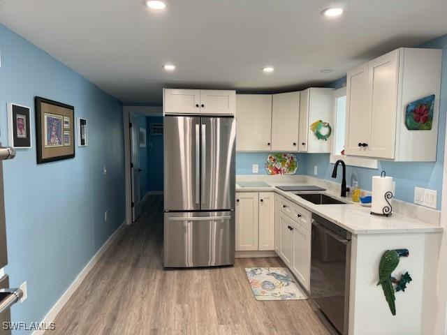 kitchen with dishwashing machine, a sink, freestanding refrigerator, and white cabinets