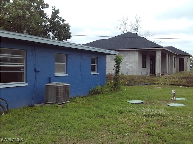 view of property exterior with central air condition unit and a lawn