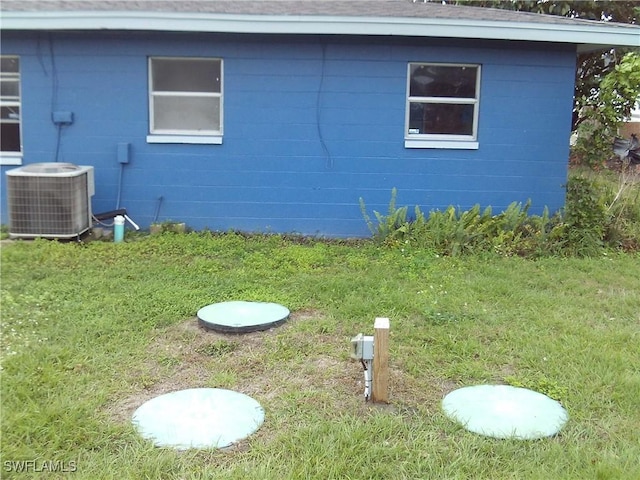 view of side of home with cooling unit and a lawn