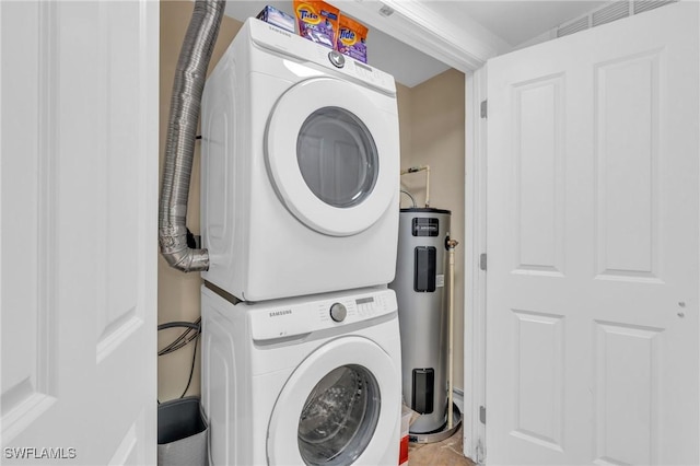 laundry room with tile patterned flooring, electric water heater, and stacked washer / drying machine