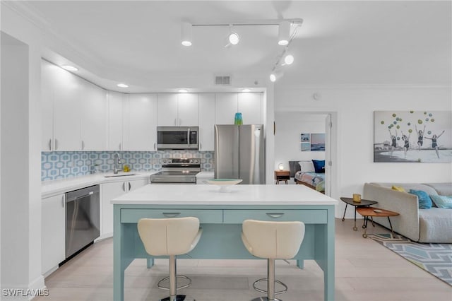 kitchen featuring a breakfast bar area, appliances with stainless steel finishes, backsplash, track lighting, and a kitchen island