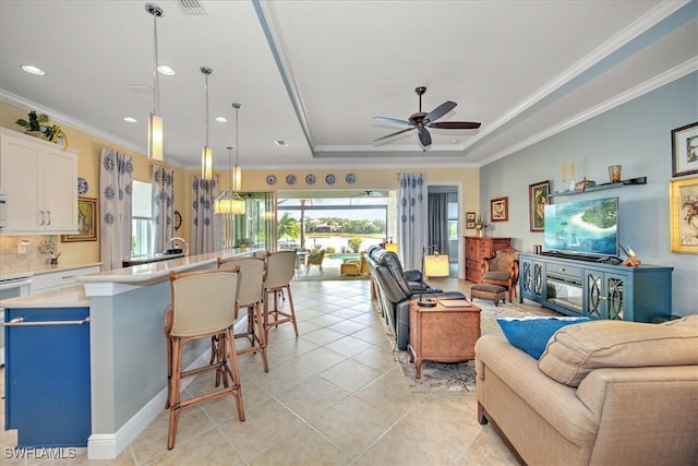 living room featuring ceiling fan, a raised ceiling, crown molding, and light tile patterned floors