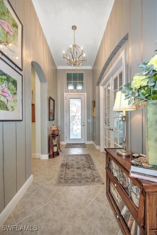 foyer featuring a chandelier, crown molding, and light tile patterned floors