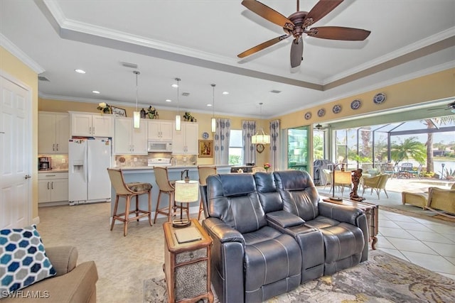 living room with light tile patterned flooring, crown molding, and a tray ceiling