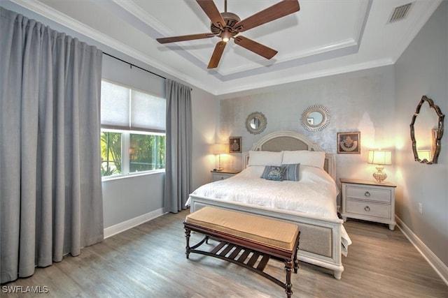 bedroom featuring ceiling fan, crown molding, hardwood / wood-style flooring, and a tray ceiling