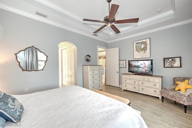 bedroom featuring ceiling fan, light hardwood / wood-style floors, a tray ceiling, and crown molding