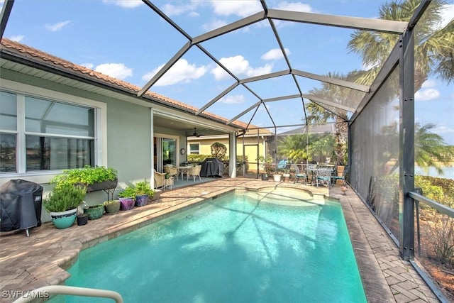 view of swimming pool featuring a patio, glass enclosure, and grilling area