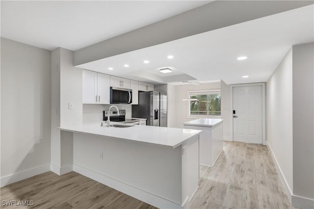 kitchen featuring stainless steel appliances, kitchen peninsula, light hardwood / wood-style flooring, and white cabinets