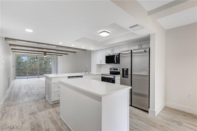 kitchen with sink, kitchen peninsula, a raised ceiling, stainless steel appliances, and white cabinets