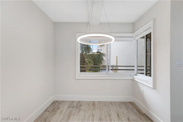 unfurnished dining area with beam ceiling and light hardwood / wood-style flooring