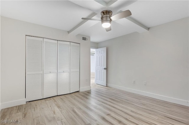 unfurnished bedroom with beamed ceiling, light hardwood / wood-style flooring, ceiling fan, and a closet