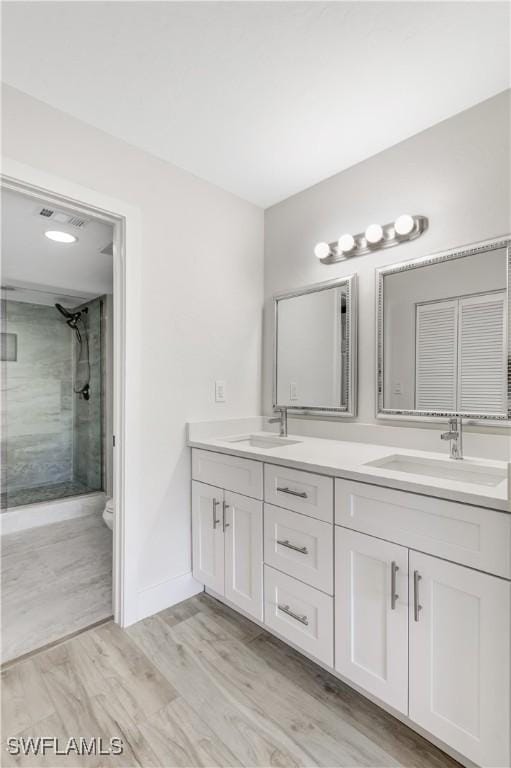 bathroom featuring vanity, hardwood / wood-style flooring, a shower with shower door, and toilet