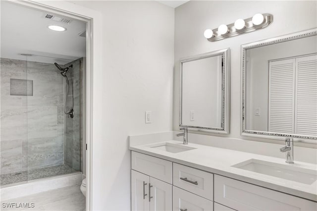 bathroom with vanity, tiled shower, and toilet