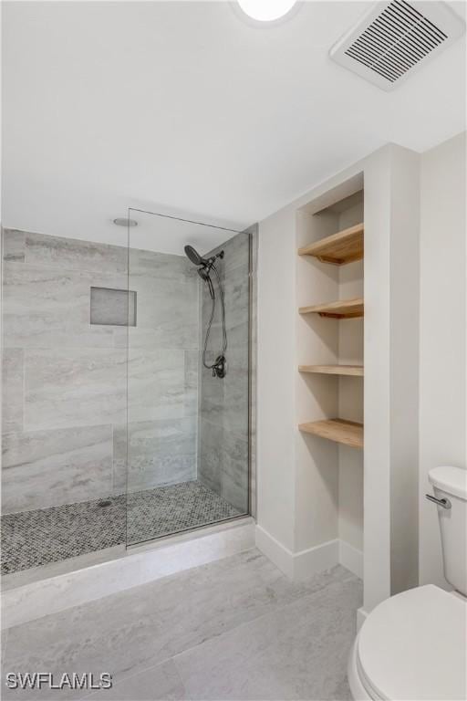 bathroom with a tile shower and toilet