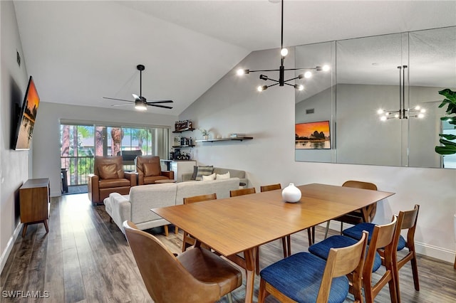 dining area featuring dark wood-type flooring, ceiling fan with notable chandelier, and vaulted ceiling