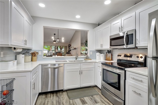 kitchen with sink, decorative light fixtures, appliances with stainless steel finishes, decorative backsplash, and white cabinets