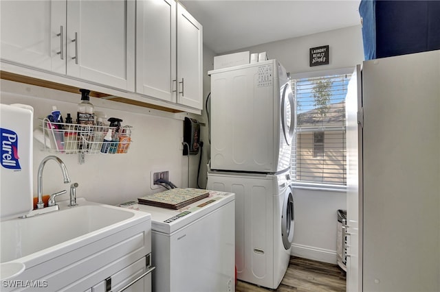 clothes washing area with sink, cabinets, stacked washer / drying machine, and light wood-type flooring