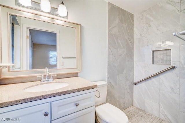 bathroom featuring tiled shower, vanity, and toilet