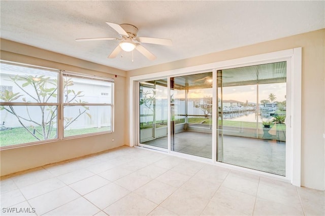 unfurnished sunroom with ceiling fan and a healthy amount of sunlight