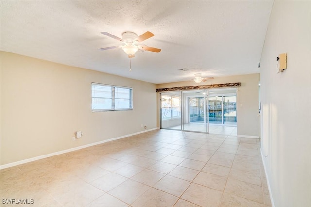 tiled empty room with a healthy amount of sunlight, a textured ceiling, and ceiling fan