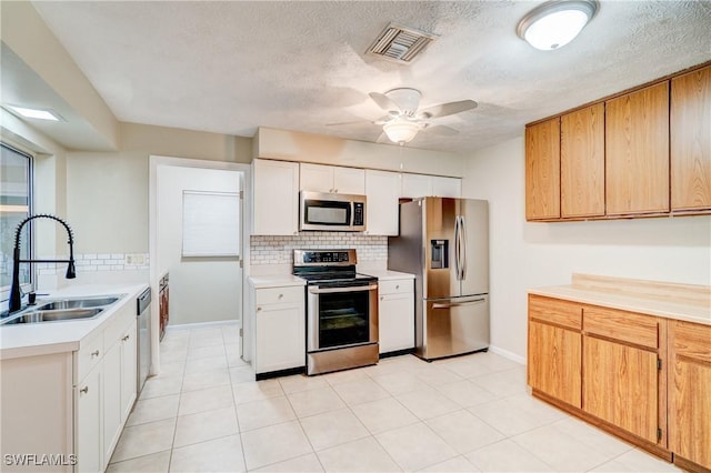 kitchen with ceiling fan, appliances with stainless steel finishes, sink, backsplash, and white cabinets