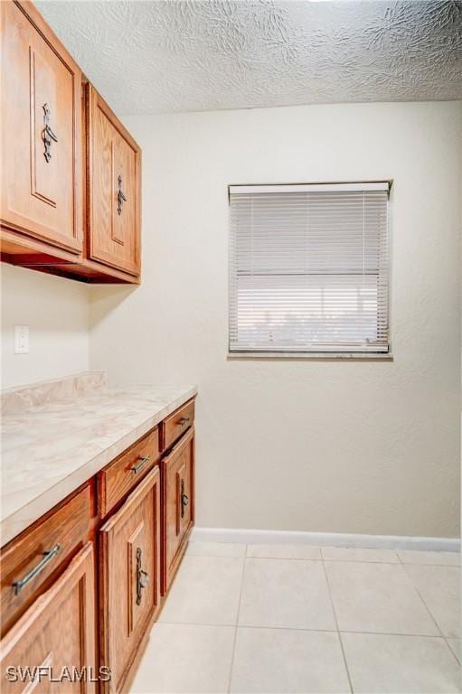 laundry area with light tile patterned floors and a textured ceiling