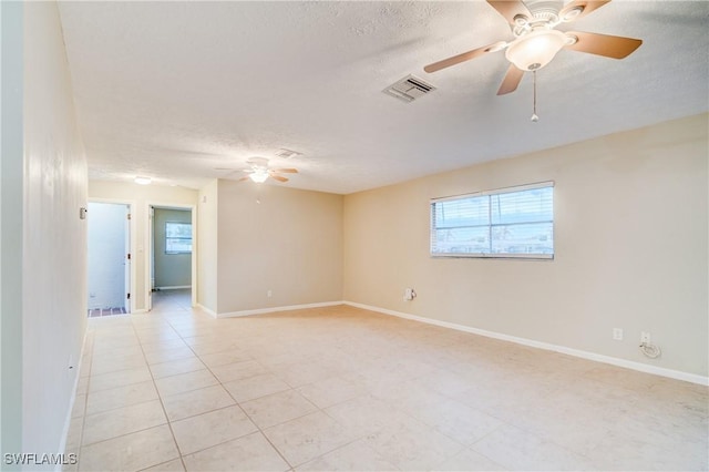 tiled spare room with a textured ceiling and ceiling fan