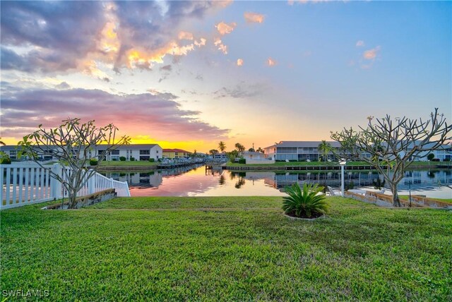 yard at dusk featuring a water view