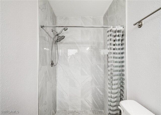 bathroom with toilet and a shower with shower curtain