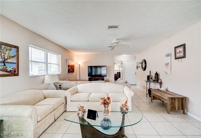 living room with ceiling fan, a textured ceiling, and light tile patterned floors