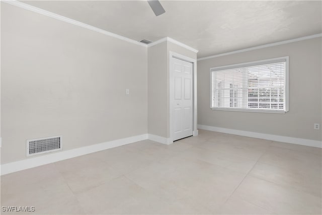 empty room with baseboards, visible vents, and crown molding