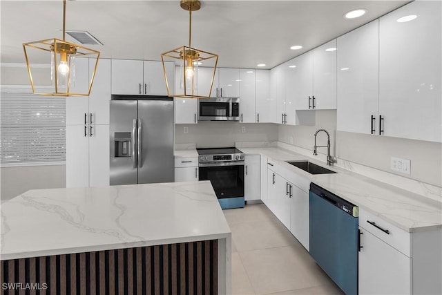 kitchen featuring stainless steel appliances, hanging light fixtures, a sink, and white cabinetry