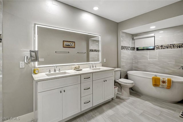 bathroom featuring vanity, toilet, tile walls, and a tub