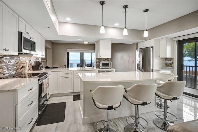 kitchen with a kitchen island, white cabinetry, appliances with stainless steel finishes, and decorative light fixtures