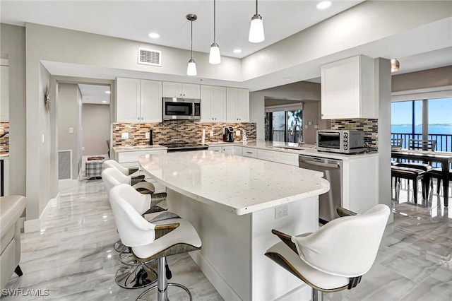 kitchen with hanging light fixtures, appliances with stainless steel finishes, sink, and a kitchen breakfast bar