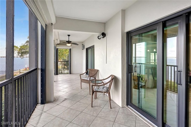 balcony featuring a water view and ceiling fan