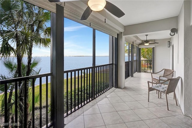 sunroom with ceiling fan and a water view