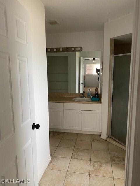 bathroom featuring walk in shower, vanity, and tile patterned flooring