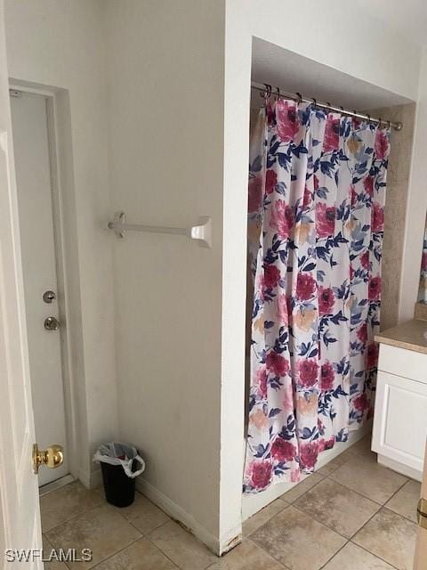 bathroom featuring tile patterned flooring, walk in shower, and vanity