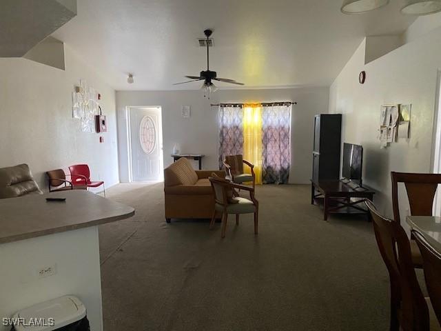 living room featuring ceiling fan, dark carpet, and lofted ceiling