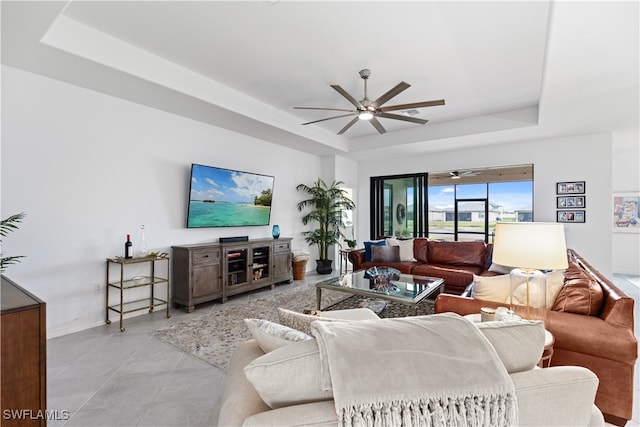 living room with a tray ceiling and ceiling fan