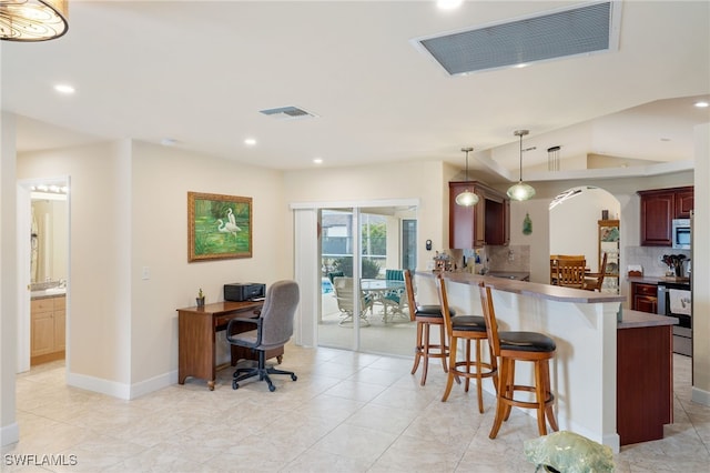 kitchen featuring hanging light fixtures, a kitchen breakfast bar, kitchen peninsula, stainless steel appliances, and backsplash