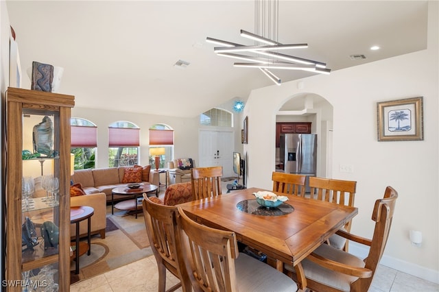 tiled dining area featuring vaulted ceiling and an inviting chandelier