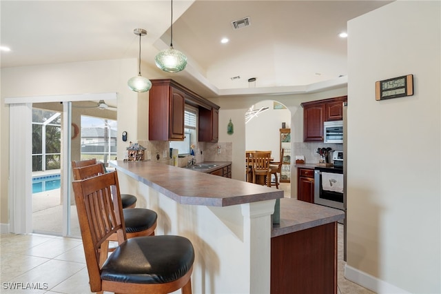 kitchen featuring appliances with stainless steel finishes, sink, backsplash, a kitchen bar, and kitchen peninsula